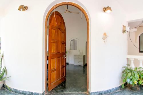 an archway leading into a hallway with a wooden door at THHPSOCIETY - Kahaani boutique Stays - Vagator Goa in Anjuna