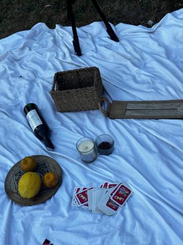 a white sheet with a basket of fruit and a bottle of alcohol at THHPSOCIETY - Kahaani boutique Stays - Vagator Goa in Anjuna