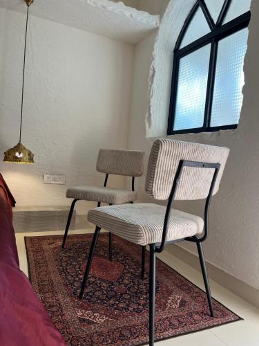 a chair and stool in a room with a window at THHPSOCIETY - Kahaani boutique Stays - Vagator Goa in Anjuna
