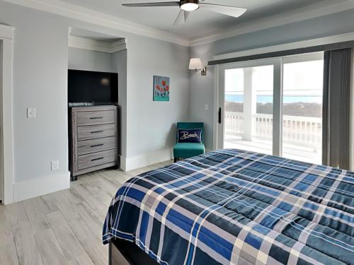 a bedroom with a bed and a television and a balcony at Dune Our Thing North Topsail Beach in North Topsail Beach