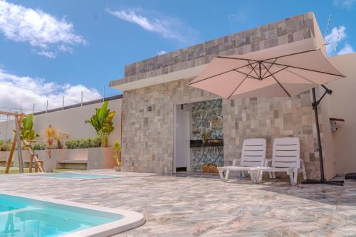 a patio with two chairs and an umbrella next to a swimming pool at Oceana Suites Aracaju in Aracaju