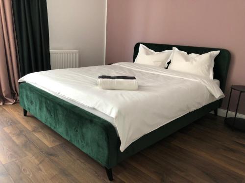 a bed with a black frame and white sheets at Saulės Tako apartamentai in Druskininkai