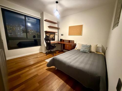 una camera da letto con un letto, una scrivania e una finestra di Departamento con patio frente a Embajada Americana a La Paz