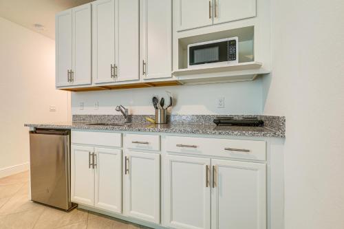 a kitchen with white cabinets and a microwave at Beach-Hop and Golf! Port St Lucie Apt with Shared Yard in Eden