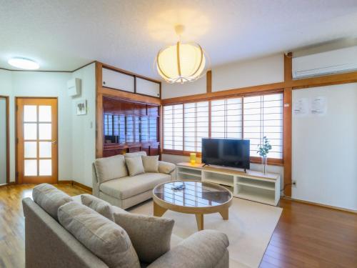 a living room with a couch and a tv at 新装開業 世界遺産と東武日光駅に至近 広いリビング 貸切 家族団体に最適 in Nikko