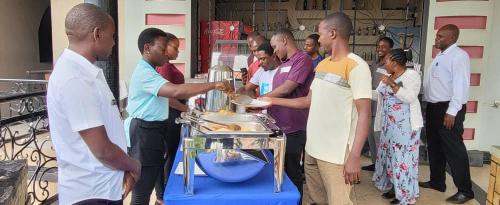 a group of people standing around a table with food at Kamwe kamwe hotel and spaa in Kasese