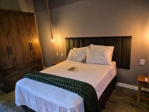 une chambre avec un grand lit avec des draps et des oreillers blancs dans l'établissement Ecoville Coracao da Serra, à Areia