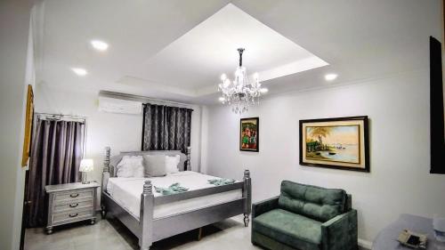 a bedroom with a bed and a chair and a chandelier at Hotel Carnaval in La Ceiba
