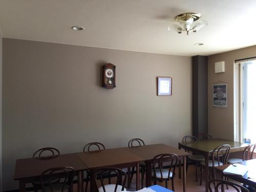 a dining room with tables and chairs and a clock on the wall at Ryokan Yamaichi in Wakkanai