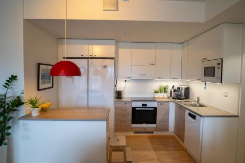 a kitchen with white cabinets and a red lamp at Loimu Arctic Home in Rovaniemi