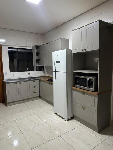 eine Küche mit Kühlschrank und Mikrowelle in der Unterkunft Casa calma e aconchegante in Tangara da Serra