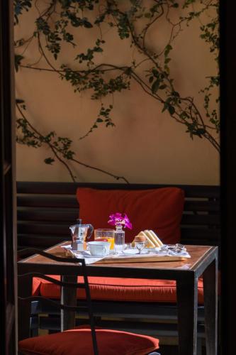 a table with a red chair and a table with food at Casa Howard Firenze - Residenza d'Epoca in Florence