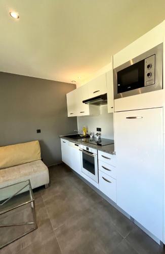 a kitchen with white cabinets and a couch at T2 cosy avec parking à 15 min de Lyon in Pierre-Bénite