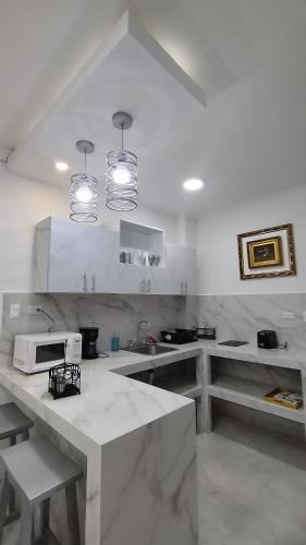 a white kitchen with a sink and a microwave at Hotel Carnaval in La Ceiba