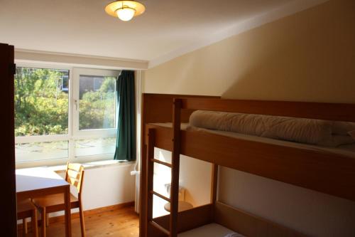 a bedroom with a bunk bed and a table and a window at Jugendhaus West in Spiekeroog