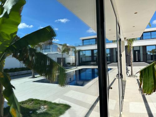 an image of a house with a swimming pool seen through a window at La Mirage Villa in Rrushkull