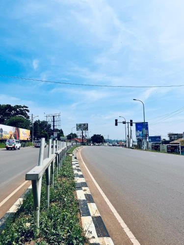 an empty highway with a fence on the side of the road at 1 minute walk to Victoria Mall in Entebbe