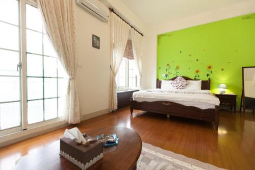 een slaapkamer met een bed en een groene muur bij Together B&B in Hualien