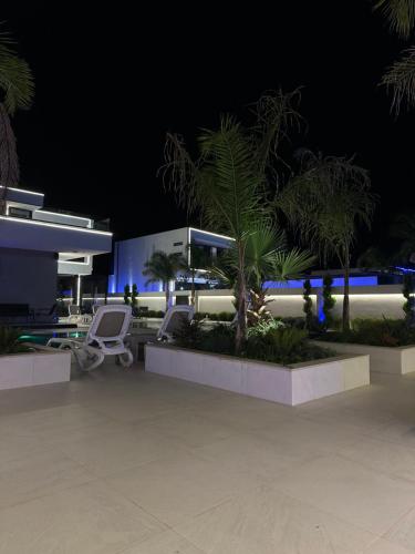 a resort with chairs and palm trees at night at Infinity Villa in Rrushkull
