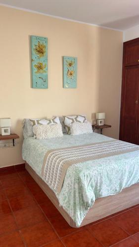 a bedroom with a large bed with two pictures on the wall at Casa Ramos in Arrecife