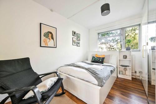 Un dormitorio con una cama y una silla y una ventana. en Riverside 1 Bed Flat with Parking at Kingston, en Kingston upon Thames