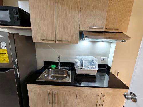 a small kitchen with a sink and a microwave at CozyNest Rentals at Brenthill Condominium in Baguio