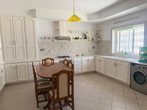 a kitchen with white cabinets and a table and chairs at Villa Hammamet in Hammamet