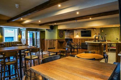 a bar with wooden tables and chairs in a restaurant at Cross Pipes Tavern and Rooms in Otley