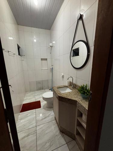 une salle de bains avec toilettes, lavabo et miroir dans l'établissement Casa ampla e confortavel, à Tangará da Serra