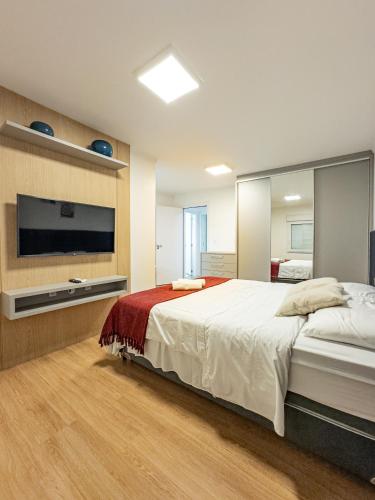 a large bedroom with a large bed and a television at Casa recém reformada, 3 quartos e com playground in Pomerode