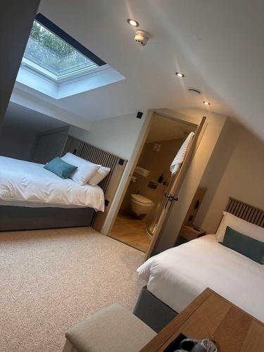 a bedroom with two beds and a bathroom with a window at Cross Pipes Tavern and Rooms in Otley