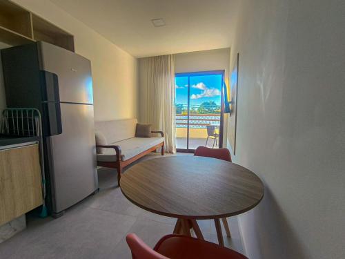 a living room with a table and a refrigerator at Village Completo na Vila de Praia do Forte in Mata de Sao Joao