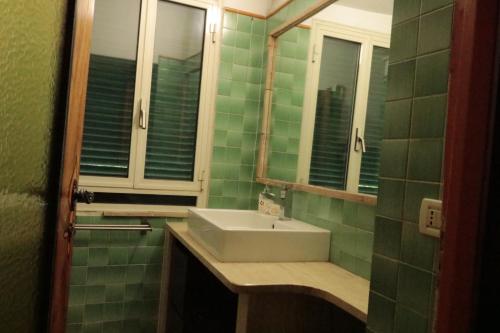 a green tiled bathroom with a sink and a mirror at Biker house in Ronciglione