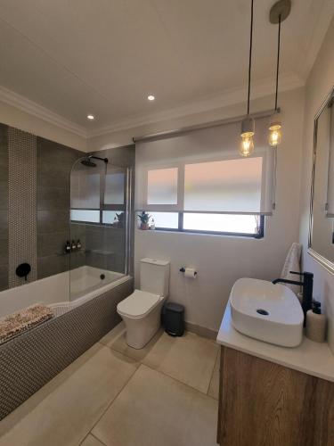 a bathroom with a toilet and a tub and a sink at Alice in Wonderland in Kimberley