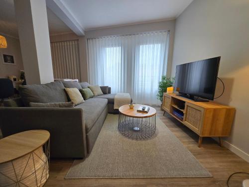 a living room with a couch and a flat screen tv at Cozy Dot Apartment in Ponta Delgada