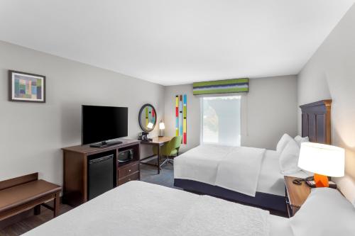 a hotel room with two beds and a television at Hampton Inn University Area, Huntington, Wv in Huntington