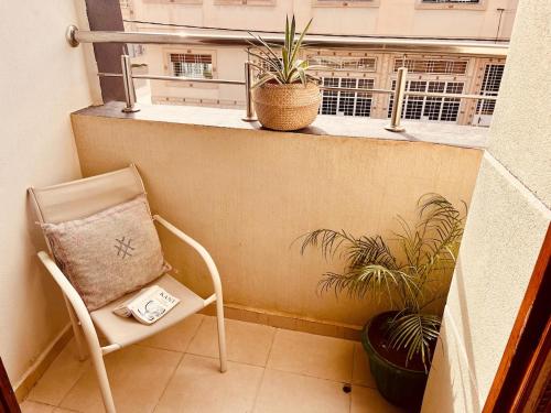 a chair on a balcony with two plants and a window at Villa De Luxe Idéalement située à Oujda in Oujda