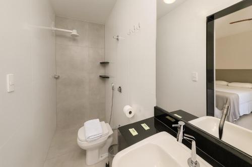 une salle de bain avec un lavabo, des toilettes et un miroir dans l'établissement Vila da Praça Pousada, à Capitólio