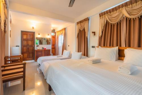 two beds in a hotel room with curtains at Biosphere by Hawks Hotels Kamadhoo Baa Atoll in Kamadhoo