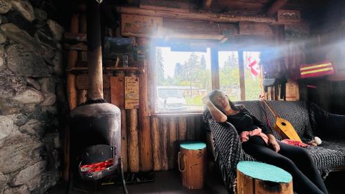 a man sitting on a couch in a room with a guitar at Heshkili huts and cabins Svaneti in Keshkili