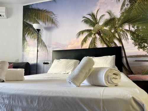 a bedroom with a bed with white pillows and palm trees at Estudio Benalmádena Costa in Benalmadena Costa