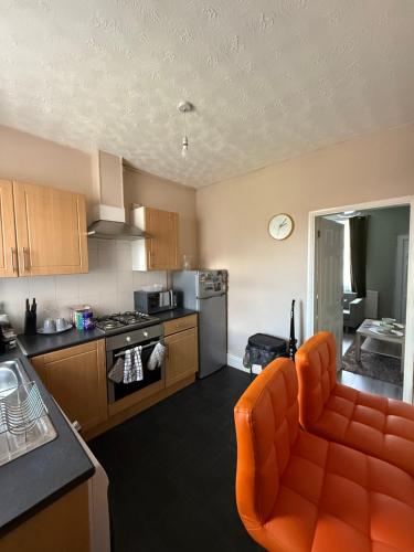 a kitchen with an orange couch and an orange chair at Cosy Room Near Train & Hospital 