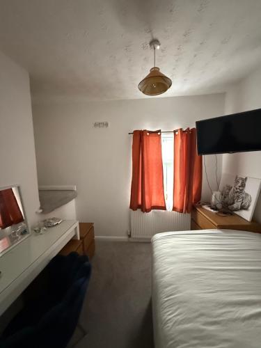 a bedroom with a bed and a window with orange curtains at Cosy Room Near Train & Hospital 