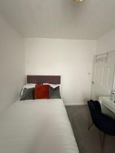 a bedroom with a white bed and a chair at Cosy Room Near Train & Hospital