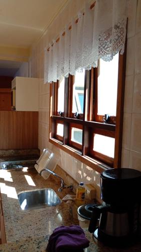 eine Küche mit einem Waschbecken und einem Fenster über einer Theke in der Unterkunft Apartamento 01 dormitório, mobiliado, equipado in São Leopoldo