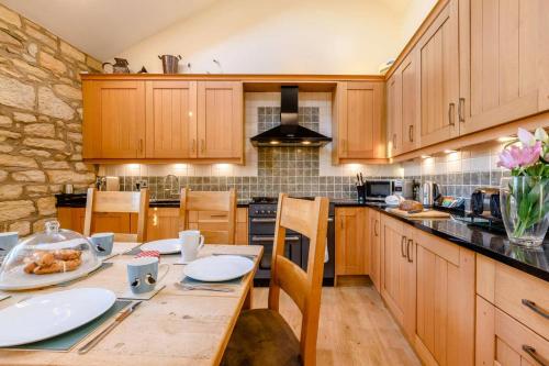a kitchen with wooden cabinets and a wooden table at Waters Edge - Warkworth in Warkworth
