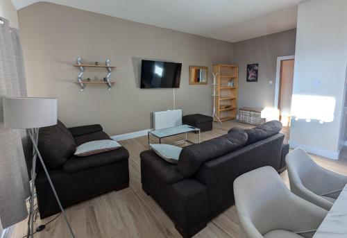 a living room with two couches and a flat screen tv at City Centre A Apartment, 2nd Floor in Belfast