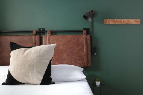 a bed with a black and white pillow and a green wall at La Ventana in San Diego