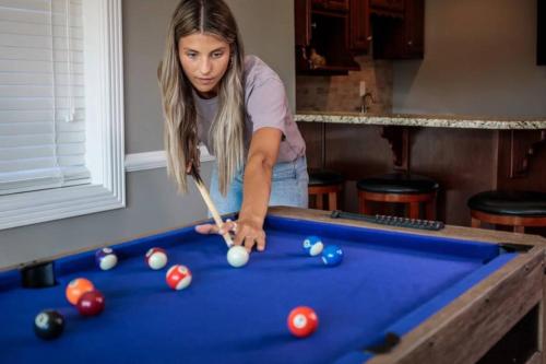 a woman playing pool with a cue on a pool table at 4BR 3Bath Game Room Harvard MIT Apt in Cambridge