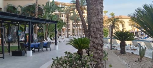 a resort with palm trees and tables and chairs at Medano beach suites in Cabo San Lucas